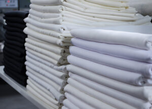 Stack of folded black and white cloths in an industrial laundry.  Cleaning service for hospitals and hotels.